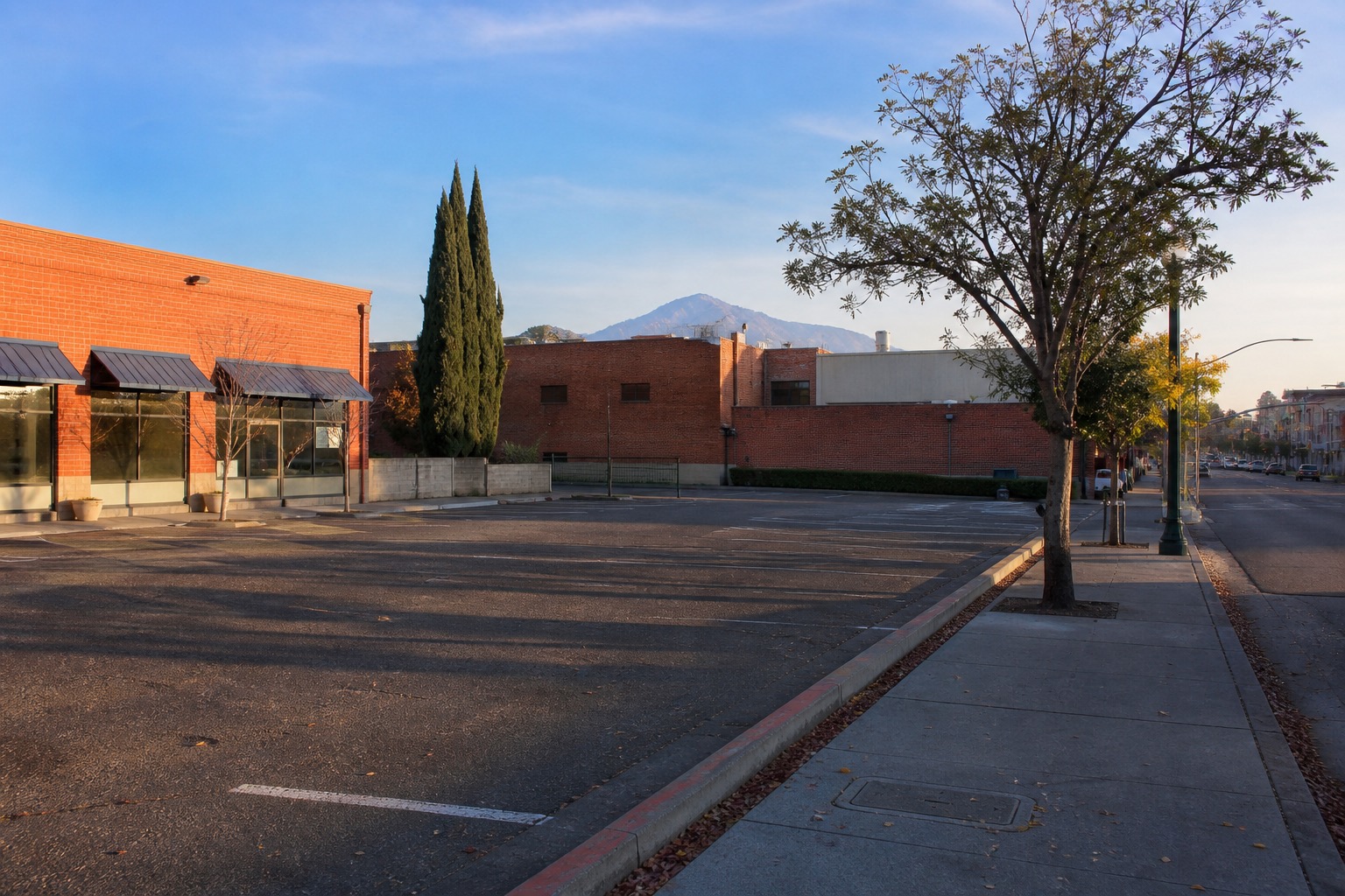 A downtown Walnut Creek surface parking lot surrounded by low-rise commercial buildings, with Mount Diablo in the hazy distance