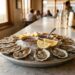 Platter of oysters on ice with lemon wedges and sauce at a restaurant bar