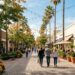 Shoppers walk past palm trees and storefronts at Broadway Plaza in Walnut Creek