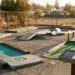 A worn putting hole with a hand-built wooden obstacle at Putter's Mini Golf in Walnut Creek